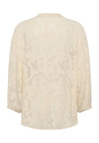 Lengvas kreminis bliusonas su gėlių tekstūra, trijų ketvirčių rankovėmis ir apvali iškirpte. Iš dalies permatomas audinys su švelniu apdaila.