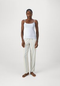 Camisola azul claro sem mangas com alças finas, combinada com calças de pijama creme e azul claro com riscas. Tecido suave e corte relaxado.