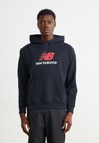 Navyblauer Kapuzenpullover aus weichem Stoff, mit einer Fronttasche und einem auffälligen roten und weißen "New Balance" Logo.