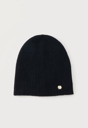 Bonnet en maille côtelée noire avec un petit emblème circulaire doré près du bord inférieur, présenté sur un fond uni clair.