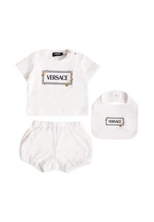 Witte katoenen set met een shirt met korte mouwen en een "VERSACE" logo, bijpassende short en een slabbetje, allemaal met gouden en zwarte accenten.