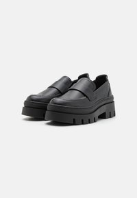 Zwarte leren schoenen met een dikke plateauzool en rechthoekige vorm, met gestikte accenten en een gladde afwerking. Geen veters of zichtbare hardware.
