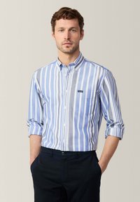 Gestreiftes Hemd in Blau und Grau mit einer Brusttasche; leichtes Material, klassischer Kragen und gerollte Ärmel.