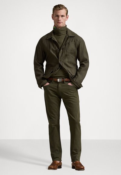 Ελιά πράσινο, υφασμάτινο μπουφάν με γιακά και μπροστινές τσέπες; ταιριαστό πουλόβερ τύπου τρύπας; εφαρμοστά ελιά παντελόνια; καφέ δερμάτινη ζώνη; καφέ παπούτσια.