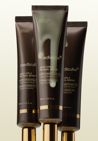 Tre brune plastikrør af MediCube Deep Vita A Retinol Serum med gyldne accenter. Lysegrønt serum drypper fra det forreste rør. Hver 30 ml.