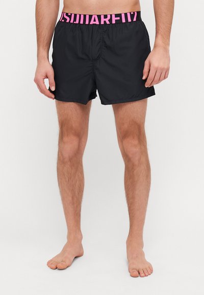 Shorts de bain noirs avec une taille élastique rose arborant le texte "SQUARE". Les shorts ont un design simple et une texture lisse.