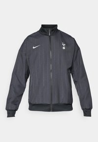 Nike sort løbejakke med høj krave, frontlynlås, tekstureret mønster, hvide logo accenter samt elastiske manchetter og kant.
