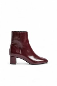 Botas de tobillo de cuero burdeos con punta afilada, tacón cuadrado y textura suave. Cuentan con una cremallera lateral para facilitar su uso.