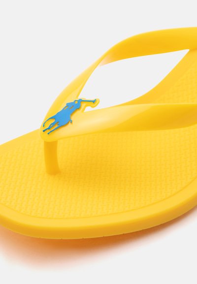 Tongs en caoutchouc jaune avec semelle texturée et logo joueur de polo bleu sur la bride.