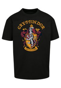 Svart bomulls-t-skjorte med et fargerikt Gryffindor-våpenskjolddesign med en løve. Elementene inkluderer røde og gull detaljer, samt en skjoldform.