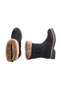 Botas de tobillo de cuero negro con un puño de piel sintética marrón y suela de goma. Presentan un emblema circular en el lateral y detalles de costura.