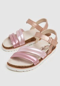 Sandalen met drie roze satijnen banden, kurk binnenzool en verstelbare metalen rosegouden enkelband. Witte rubberen zool met een gestructureerd patroon.