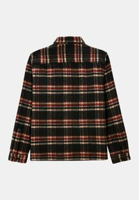 Chemise en flanelle à carreaux noire, rouge et beige avec des manches longues et des poignets à boutons, vue de dos sur un fond blanc.