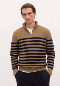 Pull en tricot rayé beige et marine avec un col montant et une fermeture éclair. Possède des poignets et un ourlet côtelés, fabriqué à partir d'un tissu texturé.