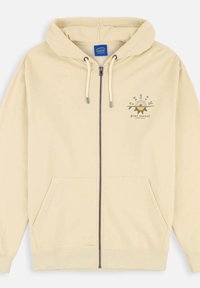 Haut zippé crème avec une capuche à cordon de serrage, des poches avant et un design graphique imprimé mettant en avant un soleil et des accents de texte. Matériau doux en coton.