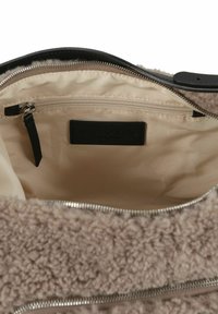 Borsa beige in peluche con texture morbida, dettagli in pelle nera, cerniere e foderatura beige. Dotata di una tasca interna con zip e etichetta del marchio.