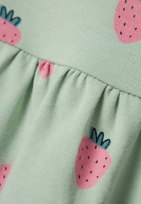 Tela verde claro con costura recogida y fresas rosas impresas con semillas negras y hojas verdes.