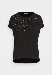 Camiseta negra de manga corta hecha de tela suave, con tachuelas metálicas en dorado y plateado dispersas en el frente, escote redondeado y dobladillo curvo.