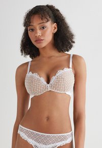 White lace bra and matching panties feature a grid pattern, floral accents, and delicate trim with adjustable straps.