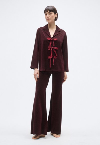 Vinrødt lounge-sæt med en langærmet top med krave og tre sløjfedetaljer, kombineret med udsvungne bukser i samme strukturerede stof.