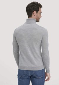 Grauer Rollkragenpullover aus weichem Strickmaterial, mit taillierter Passform, geripptem Kragen und langen Ärmeln, kombiniert mit blauen Jeans.