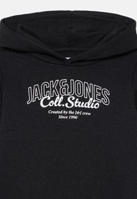 Črna kapuca z velikim belim logotipom, ki prebere "JACK & JONES Coll. Studio", z dodatnim manjšim besedilom spodaj, gladka tekstura tkanine.