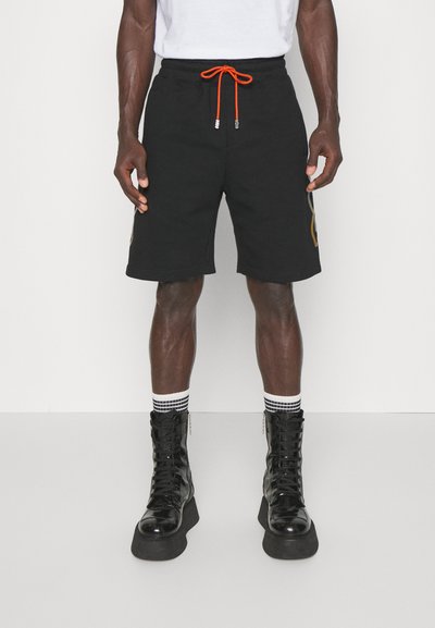 Μαύρα σορτσάκια τρόποι με ελαστική μέση, πορτοκαλί κορδόνι και γραφικό στο πλάι. Συνδυασμένα με ψηλές μαύρες πλατφόρμες και ριγέ καλσόν.