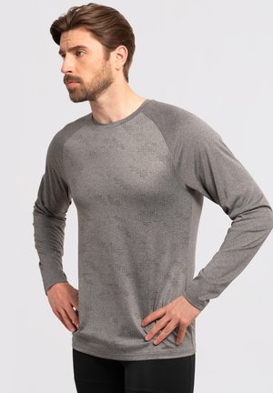 Maglietta atletica grigia a maniche lunghe con un motivo testurizzato, maniche raglan a contrasto, e un design aderente. Tessuto morbido con una leggera lucentezza.
