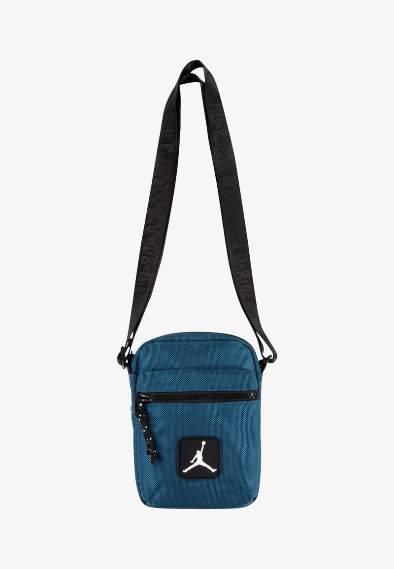 Teal crossover veske laget av strukturert stoff, med svart glidelåslukking, justerbar stropp, og en hvit Jumpman-logo på en svart lapp.