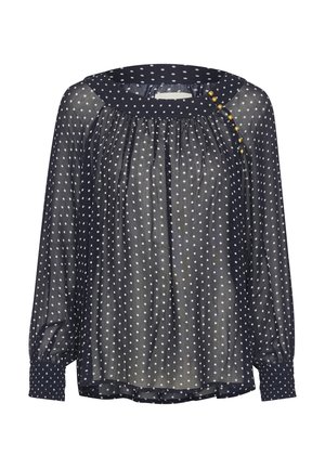 Blouse transparente bleu marine ornée de pois blancs, col rond avec accents en boutons, et manches longues avec des poignets ajustés.