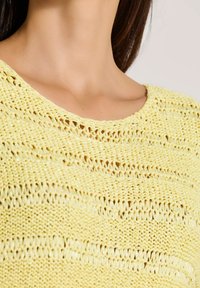 Geel gebreid sweater met een losse weving, voorzien van een ronde halslijn en diagonale streepjespatronen in de textuur.