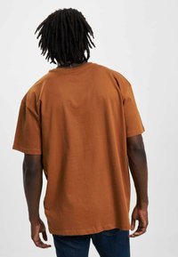 Mørkebrun bomulds T-shirt med korte ærmer og en afslappet pasform, med en ensfarvet ryg uden mønstre eller pynt.