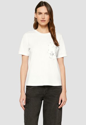 T-shirt en coton blanc à manches courtes et poche sur le devant, ornée d'un motif floral brodé et de clous décoratifs. Design décontracté.