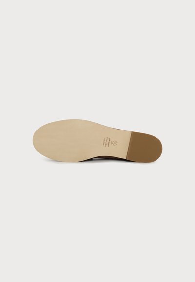 Vue de la semelle de chaussure avec une semelle extérieure beige et un talon marron, comportant un texte indiquant le style, la taille et le logo de la marque.