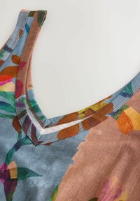 Tílko s květinovým vzorem a výstřihem do V, v živých barvách jako modrá, oranžová a zelená. Měkká tkanina s kontrastním lemem u výstřihu.