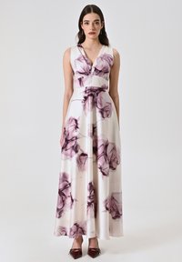 Robe maxi en tissu crème, arborant un imprimé floral vivant en violet et bordeaux. Décolleté en V et taille cintrée avec une jupe évasée.
