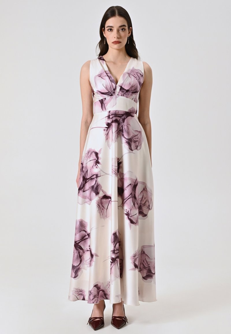 Robe maxi en tissu crème, arborant un imprimé floral vivant en violet et bordeaux. Décolleté en V et taille cintrée avec une jupe évasée.