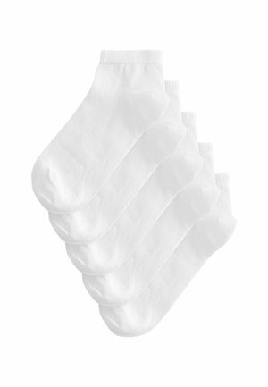 Vijf paar eenvoudige witte enkelsokken, licht overlappend gestapeld op een witte achtergrond.
