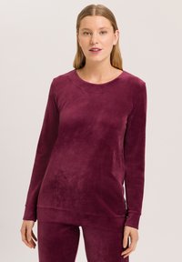 Top de manga larga color ciruela en material suave y aterciopelado, con cuello redondo y corte relajado, que presenta mangas con puños y una textura lisa.