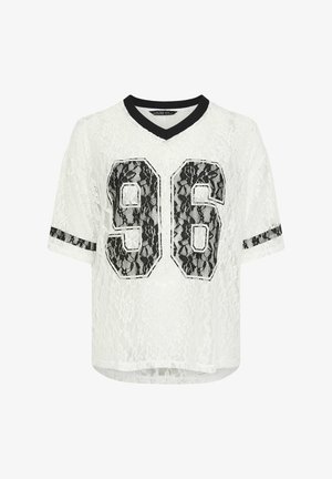 Witte kanten top met korte mouwen, zwarte afwerking op de kraag en mouwen, met een groot zwart kanten nummer "96" op de voorkant.
