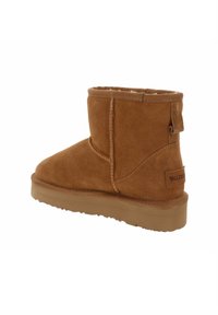 Stivale alla caviglia in suede marrone con forma arrotondata, rivestimento morbido e suola piatta in gomma. Presenta dettagli di cucitura e un tassello sul retro.