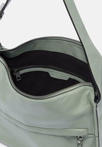 Borsa in pelle verde chiaro con un interno in tessuto nero. Presenta un sComparto con cerniera e una tasca frontale con una finitura testurizzata.
