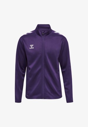 Lilla sportstrøje med fuld lynlås med hvidt logo og chevronstriber på skuldrene, lange ærmer og sidelommer.