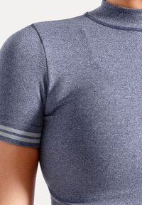 Kortærmet top lavet af tekstureret, mørkeblåt stof; har en høj krave og grå accentstriber på ærmerne.