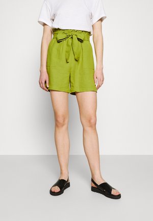 Shorts en lin verts avec une taille à nouer, dotés de deux poches avant et d'une coupe décontractée. Associés à des sandales plates noires pour un look décontracté.