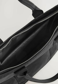Schwarze Reißverschlusstasche mit stabilen Griffen, aus glattem Material gefertigt. Das Innere zeigt gefütterte Fächer ohne sichtbare Muster oder Verzierungen.