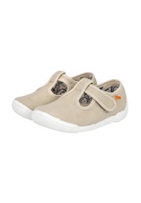Zapatillas de lona beige con un upper texturizado, correa elástica y suela de goma blanca. Presenta un interior con un patrón y un pequeño detalle de logo naranja.