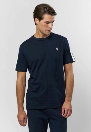 Tumed sinine t-särgi, mis on valmistatud puuvillast, lühikeste varrukatega, õlgadel valgete triipudega ja rinnal väikese broderitud logoga.