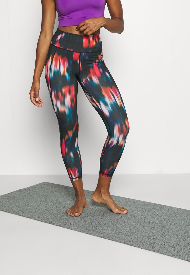 Svarta leggings med ett färgglatt abstrakt mönster i röd, blå och vit, med hög midja och tajt passform. Matchat med en lila crop-top.