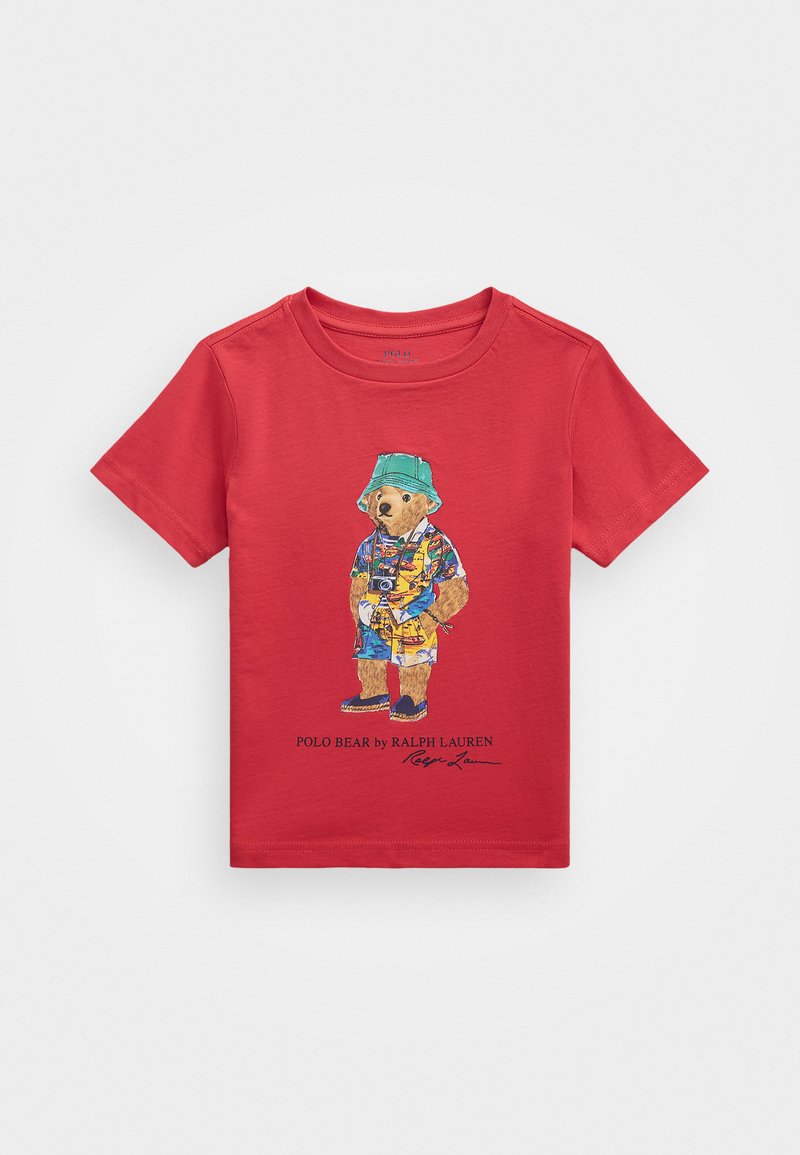 Red cotton t-shirt featuring a graphic of a bear in colorful beach attire, with a camera and sandals, and "Polo Bear by Ralph Lauren" text.